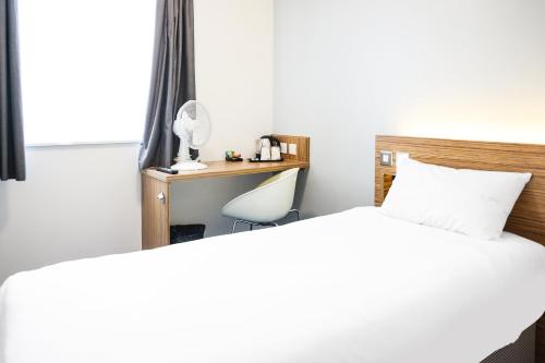 a bedroom with a bed and a desk with a lamp at GO2 Lancaster Centre Hotel by OYO in Lancaster