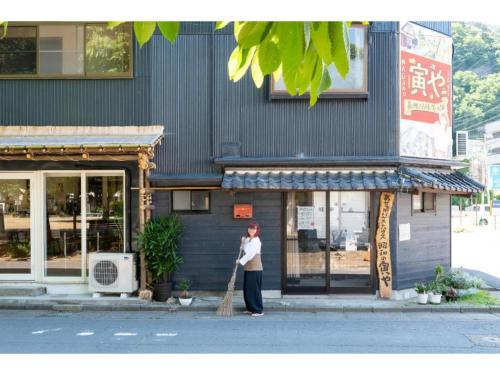 a woman standing in front of a building with a broom at Showa No Toraya - Vacation STAY 61491v in Chikuma