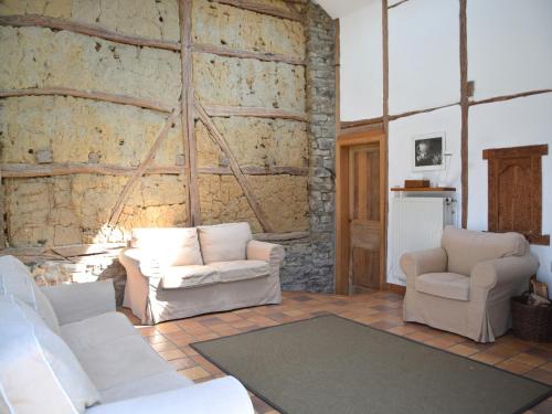 a living room with two white chairs and a stone wall at Heritage Holiday Home in Roumont in Roumont