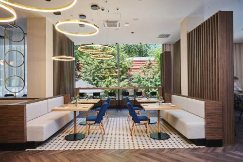 a restaurant with tables and chairs and a large window at voco Katowice by IHG in Katowice