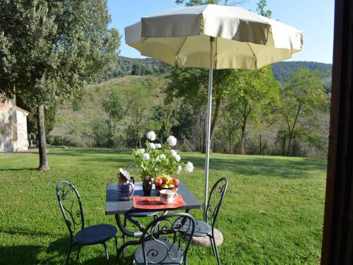 a table and chairs under an umbrella in the grass at Tuscan Retreat in Montalceto in Serre di Rapolano