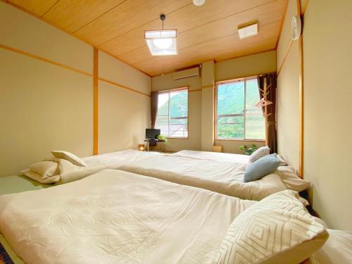 two beds in a room with two windows at Succeeding Gorge Onsen Hall - Vacation STAY 74512v in Inuma