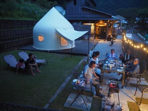 a group of people sitting at tables in a yard at night at Ashigarakami-gun - Camp - Vacation STAY 84740v in Hokizawa