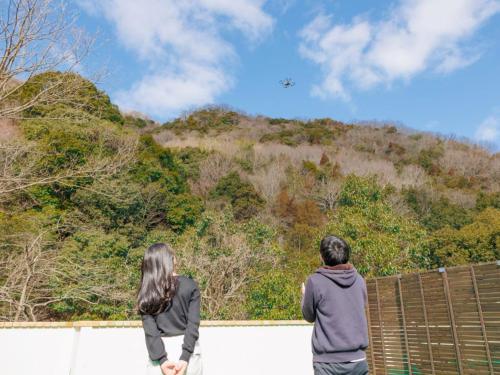 two people standing on a fence looking at a kite in the sky at Riverside Glamping Kamiseno - Vacation STAY 92767v in Hiroshima