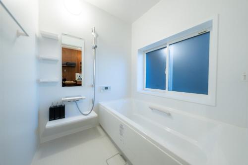 a white bathroom with a tub and a window at The View Minamiboso - Vacation STAY 16265 in Minamiboso