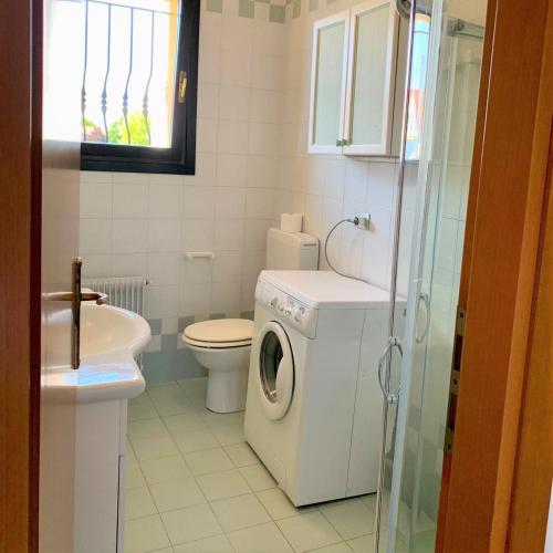 a bathroom with a washing machine and a toilet at Tamerici in Cavallino-Treporti