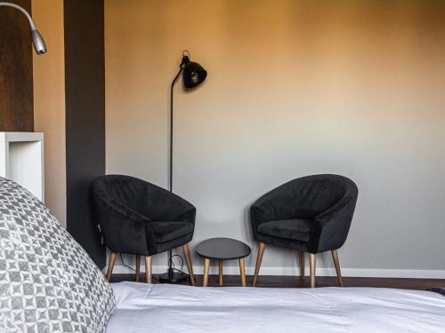 two black chairs and a lamp next to a bed at Spacious Stay in Lemberg in Lemberg