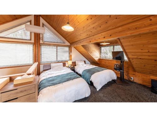 two beds in a room with wooden walls and windows at Kurokawa Mori No Kiki - Vacation STAY 14693v in Aso