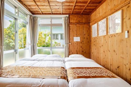 zwei Betten in einem Zimmer mit Fenster in der Unterkunft Kayo BASE in Nago
