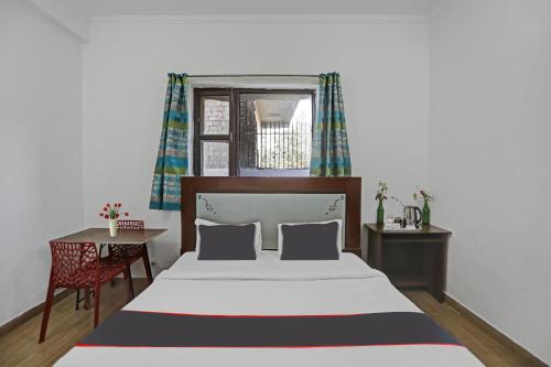 a bedroom with a bed and a table and a window at Hotel Naveen Stay in Manesar