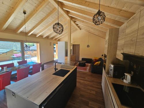 a kitchen and living room with wooden ceilings and a table at Appartement Cosy & Calme au Cœur de la Gruyère in Jaun
