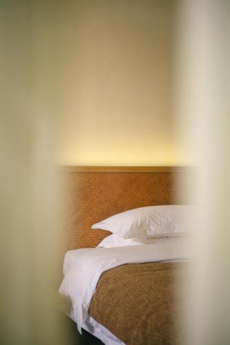 a bed with white pillows and a wooden headboard at 涠洲岛隐拙山与澜海景酒店 in Weizhouxu