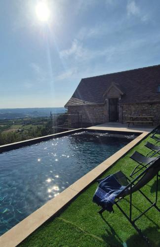 a swimming pool with two chairs and a house at La Marilène Grange avec vue exceptionnelle ! in Loubressac