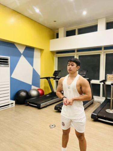 a man standing in a gym with his arms crossed at JFam Suites, C1-5L 1BR , Up To 7 Pax in Biñan