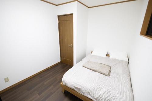 a bedroom with a bed with white sheets and a wooden floor at Tokorozawa - House - Vacation STAY 16364 in Tokorozawa