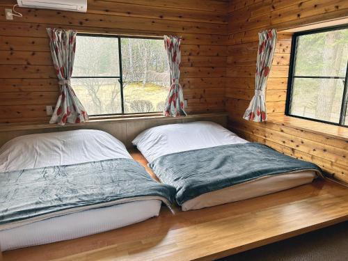 two beds in a log cabin with two windows at HARUNA VILLA - Vacation STAY 27961v in Kita-karuizawa