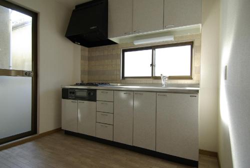 a kitchen with white cabinets and a sink and a window at Minpaku =SAKURA= - Vacation STAY 16462 in Osaka