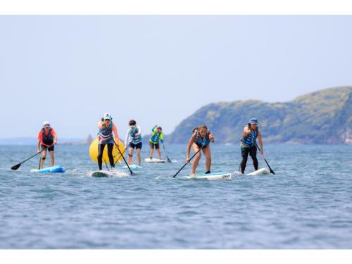 a group of people are paddle boarding on the water at OCEAN FRONT TATEYAMA - Vacation STAY 61331v in Tateyama