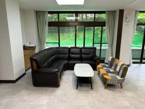 a living room with a black leather couch and a table at GONZOU-HOUSE - Vacation STAY 42967v in Zao