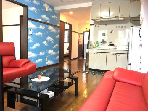 a living room with a red couch and a kitchen at KY Apartment - Vacation STAY 40189v in Naha