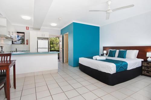 a bedroom with a king sized bed and a kitchen at Cairns City Palms in Cairns