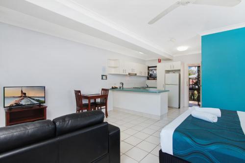 a living room with a couch and a kitchen at Cairns City Palms in Cairns