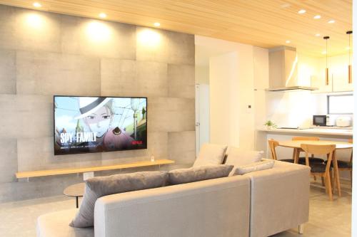 a living room with a couch and a tv on a wall at emma green - Vacation STAY 55704v in Sesoko
