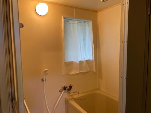 a bathroom with a tub and a shower with a window at Chambord Kyomachi 102, 201, 202, 205, 207 - Vacation STAY 44168v in Kumamoto