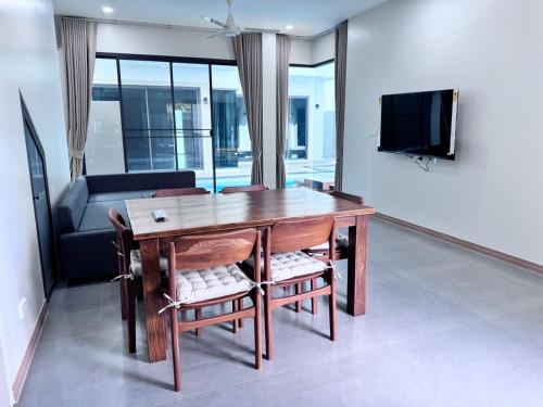 a living room with a wooden table and chairs at Bay Sand Villa by Jai House Phuket in Ban Klang