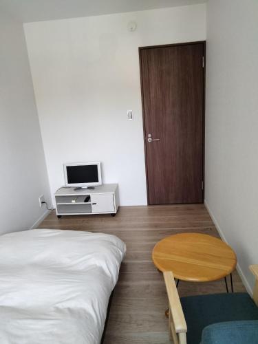 a bedroom with a bed and a table and a door at Guesthouse Senba - Vacation STAY 16626 in Mito