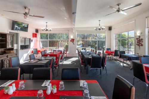 a restaurant with tables and chairs and windows at The Grampians Motel in Halls Gap
