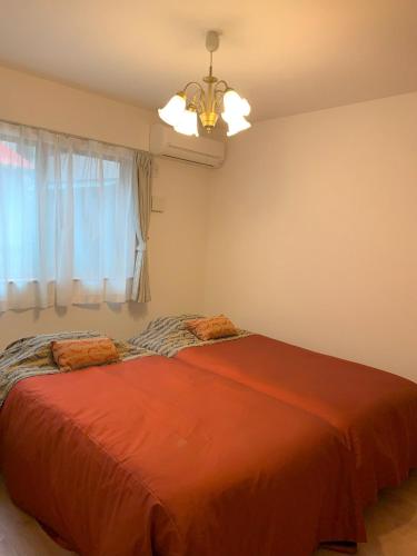 a bedroom with a large orange bed with a chandelier at Calm Enoshima 102 - Vacation STAY 61941v in Kamakura
