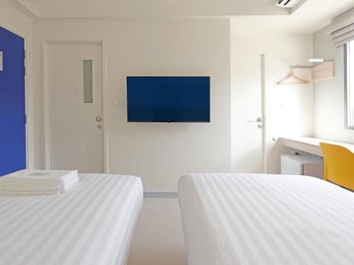 two beds in a room with a tv on the wall at HOP INN Phrae in Phrae