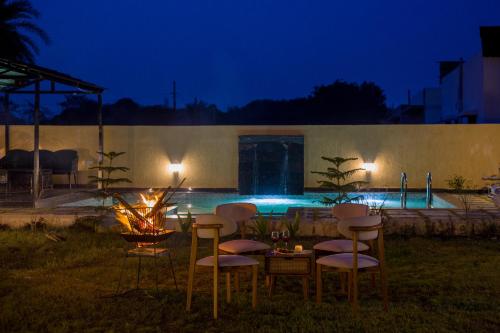 a table and chairs in a yard at night at The Bliss Nestlewood 2-BHK Villa With Private Pool, Lush Garden & Poolside Gazebo in Udaipur