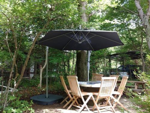 a table with four chairs and an umbrella at The No,10 Forest Haven Villa - Vacation STAY 67009v in Tatsutori