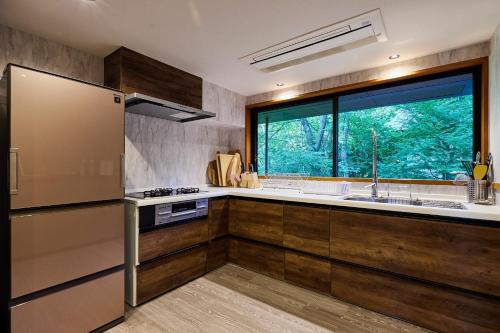 a kitchen with wooden cabinets and a large window at The No,10 Forest Haven Villa - Vacation STAY 67009v in Tatsutori