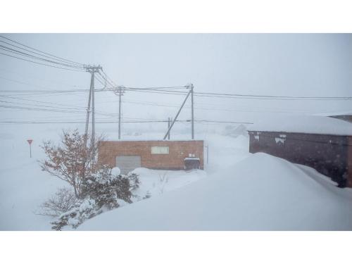 a building covered in snow next to a tree at MUSH ROOMS - Vacation STAY 75002v in Higashikawa