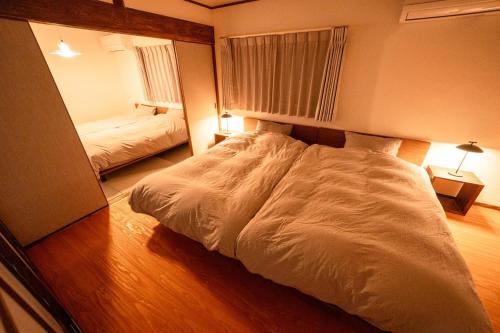 a bedroom with a large white bed and a mirror at Shuka - Vacation STAY 75085v in Aso