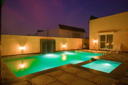 a swimming pool in the middle of a house at night at The Bliss Nestlewood 2-BHK Villa With Private Pool, Lush Garden & Poolside Gazebo in Udaipur