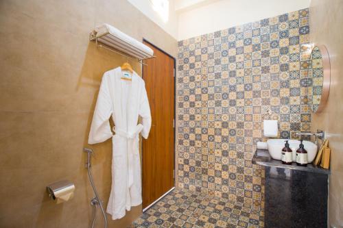a bathroom with a robe hanging on a wall at The Bliss Nestlewood 2-BHK Villa With Private Pool, Lush Garden & Poolside Gazebo in Udaipur