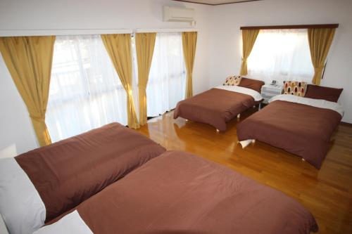 three beds in a room with windows and wooden floors at Fukutokukashiya - Vacation STAY 16907 in Kagoshima