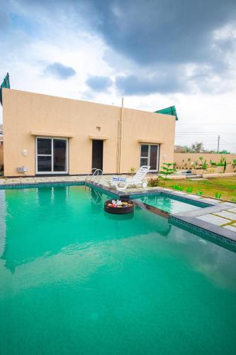 a swimming pool in front of a building at The Bliss Nestlewood 2-BHK Villa With Private Pool, Lush Garden & Poolside Gazebo in Udaipur