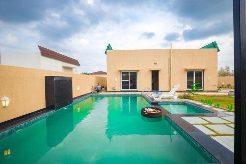 a swimming pool in front of a house at The Bliss Nestlewood 2-BHK Villa With Private Pool, Lush Garden & Poolside Gazebo in Udaipur