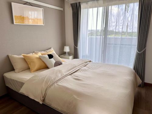 a bedroom with a large white bed with a window at Kin-Con-Kan - Vacation STAY 05378v in Nanjo