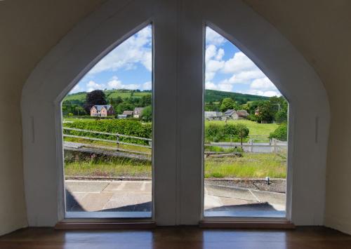 een boogvenster met uitzicht op een veld bij Station Cottage in Bucknell