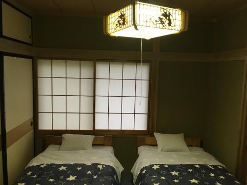 - 2 lits dans une chambre avec une fenêtre et un lustre dans l'établissement Tsumagoi Bessou Life Sanso 2 - Vacation STAY 14930v, à Tsumagoi