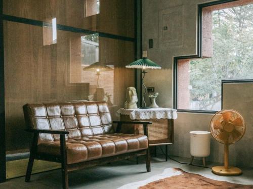 a living room with a leather couch and a table at 德旅店 Dehostel in Pingtung City