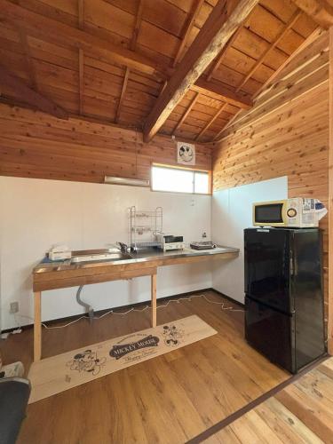 a kitchen with a table and a black refrigerator at Bamboo Camp Site "Isumi Genji Firefly Village" - Vacation STAY 08175v in Ōtaki