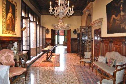 a living room with a chandelier and a room with chairs at Palazzetto Pisani Grand Canal in Venice