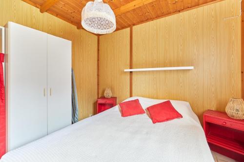 a bedroom with a white bed with two red pillows at Le Jasmin à la Douceur de vivre in Valsemé